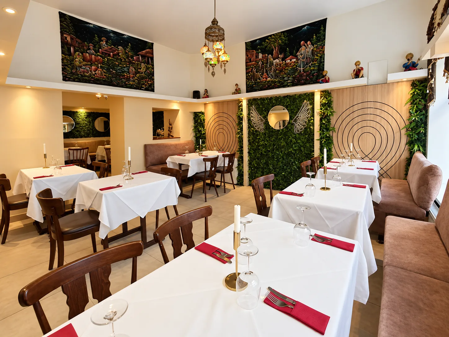 Gastraum von Bollyfood mit gedeckten Tischen, grüner Pflanzenwand und indischen Wandbildern